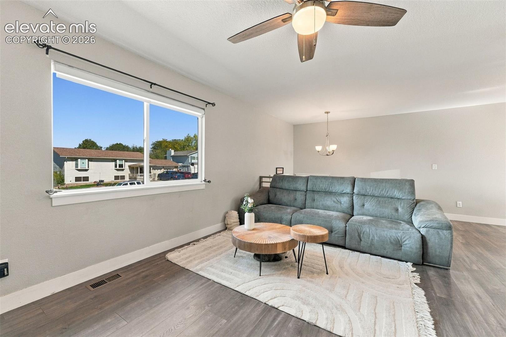 Large window with white trim, ceiling fan with integrated lighting, wood-finish flooring, and recessed ceiling lighting