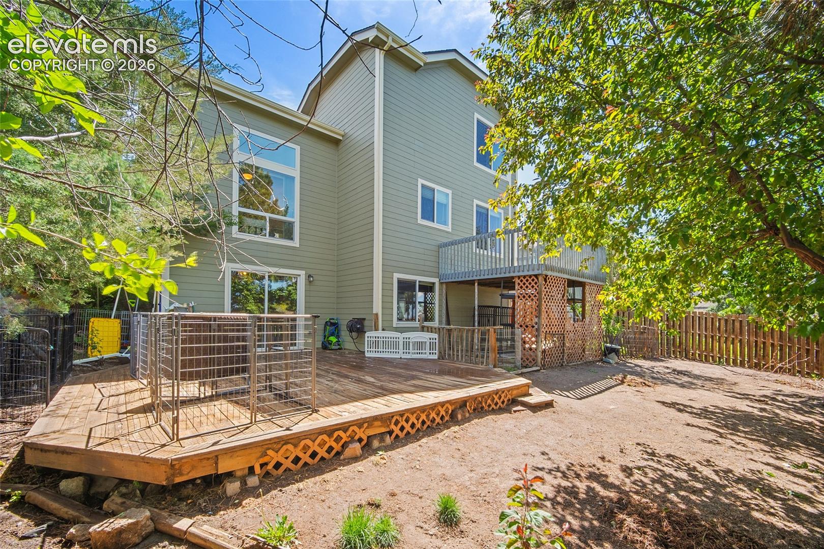 Rear exterior featuring a multi-level wood deck, an upper-level balcony, and a ground-level patio with lattice screening