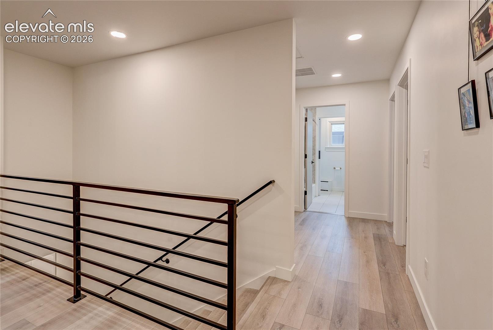 Recessed lighting, wood-finish flooring, and black metal railing
