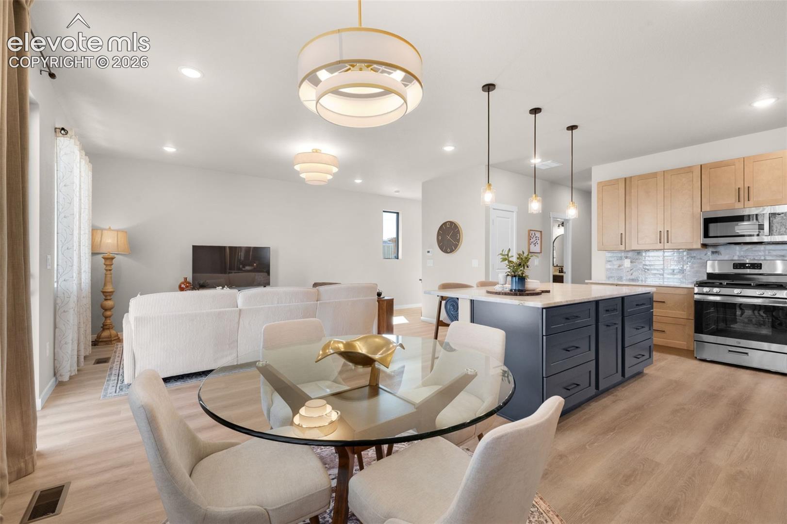 Open-concept living space featuring wood-finish flooring, recessed lighting, and a modern kitchen island with pendant lighting