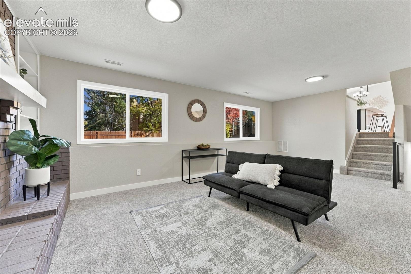 Interior space featuring a brick-surround fireplace, carpeting, recessed ceiling lighting, and large windows