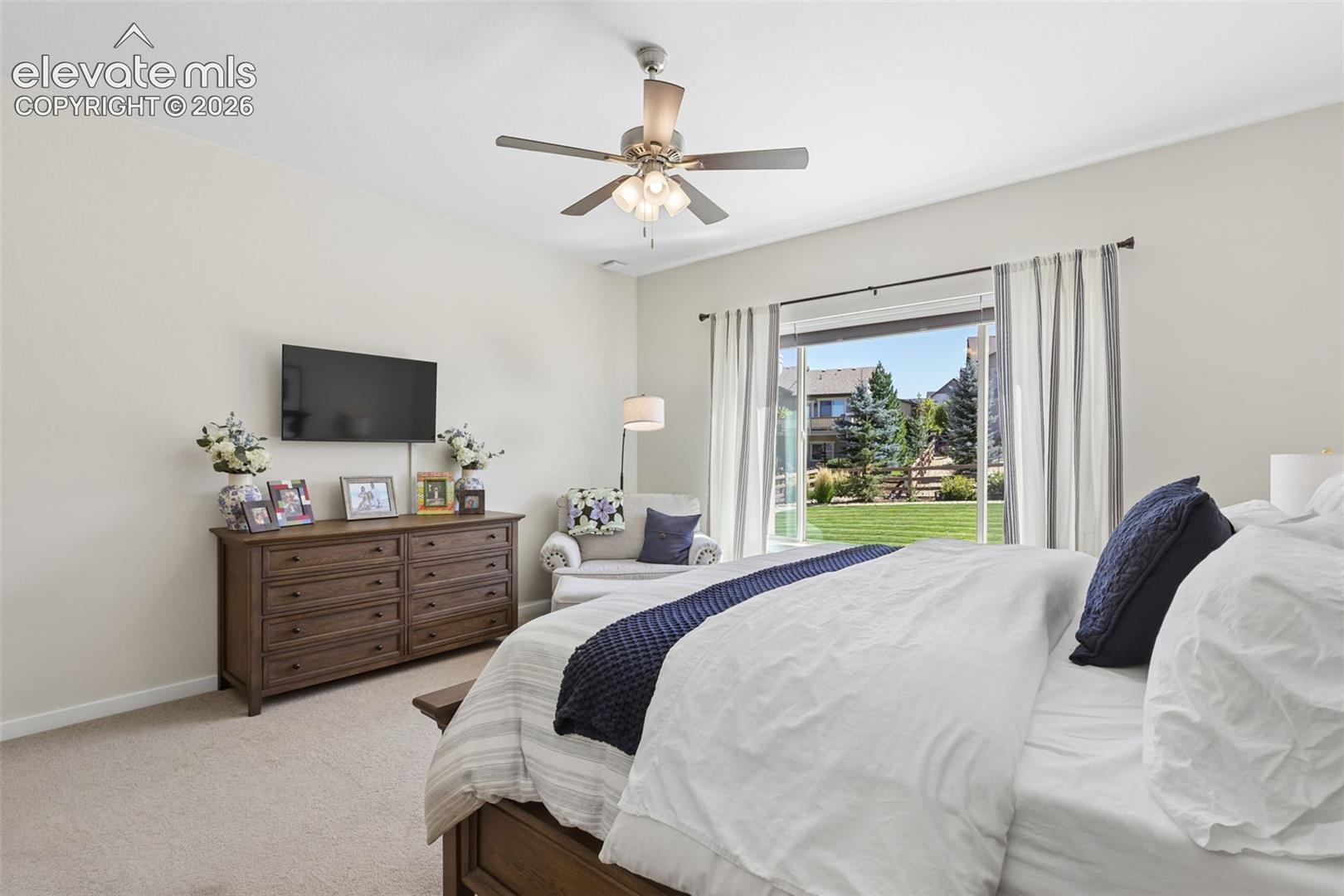 Ceiling fan, wall-mounted television, sliding glass door, and carpeted flooring