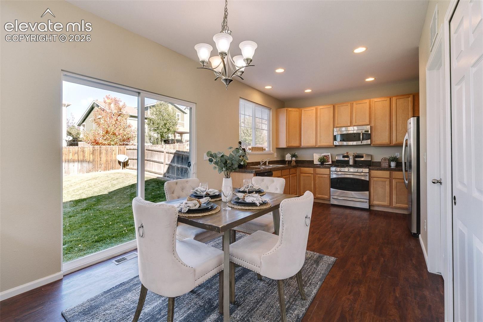 Kitchen featuring light wood-finish cabinetry, stainless steel appliances, recessed lighting, sliding glass door, and wood-finish flooring
