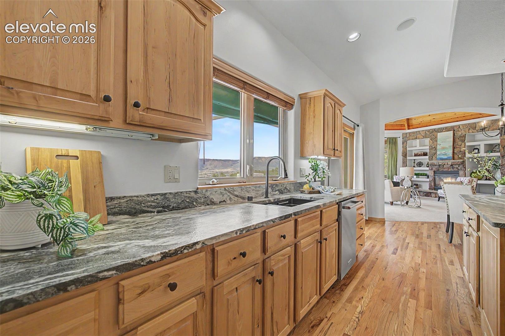 Kitchen featuring wood-finish cabinetry with black hardware, stone countertops, a black sink with a gooseneck faucet, and stainless steel appliances