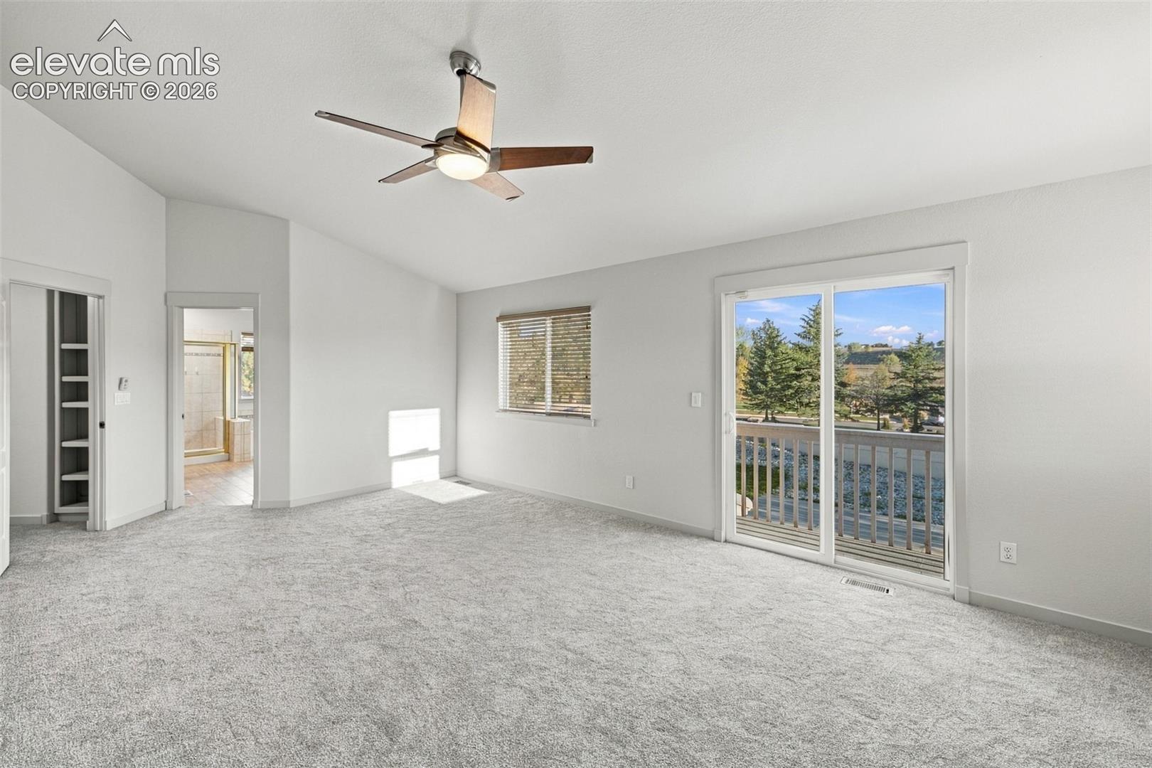 Vaulted ceiling, ceiling fan with integrated lighting, wall-to-wall carpeting, sliding glass door with exterior access, and built-in shelving