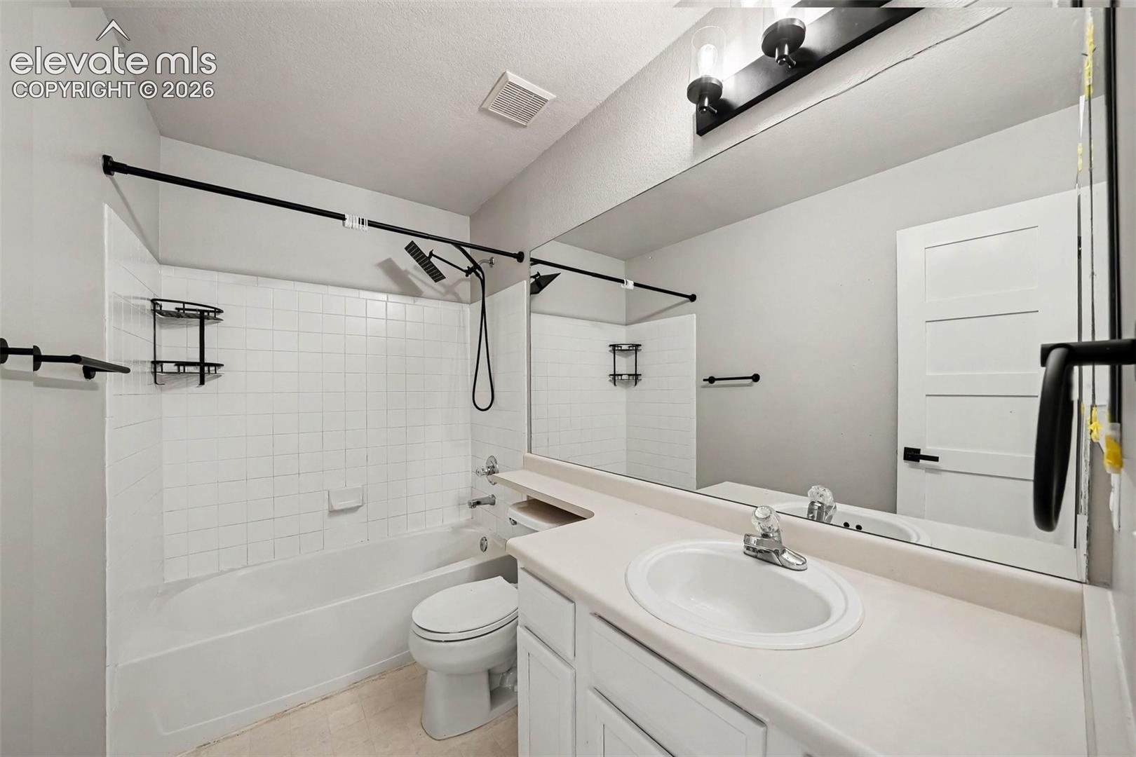 Bathroom featuring a full-width vanity mirror, a white single-basin sink, and white cabinetry