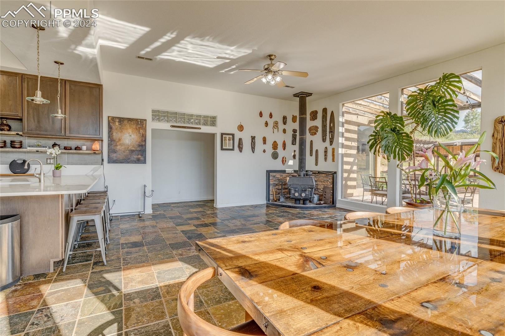 Dining area with sink, dark tile floors, ceiling fan, and a wood stove