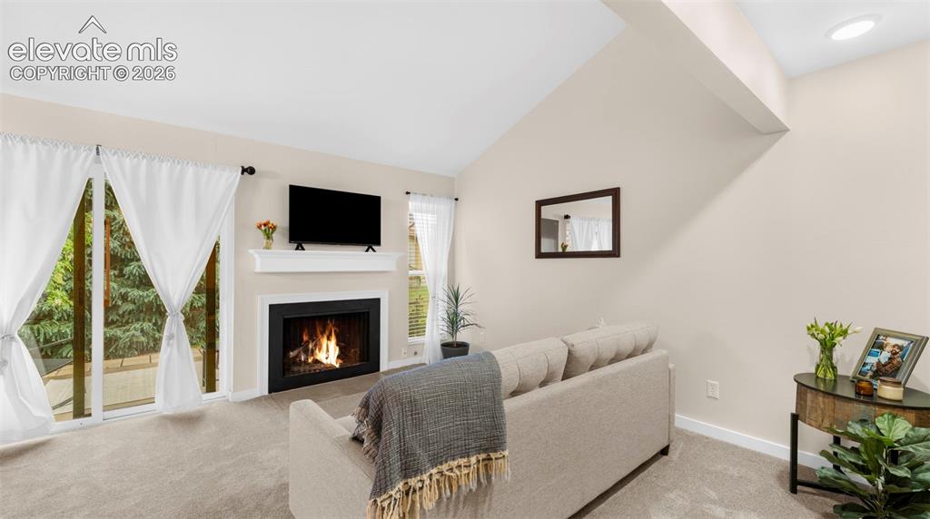 Living area featuring a fireplace with a white mantel, mounted television, and light gray wall paint