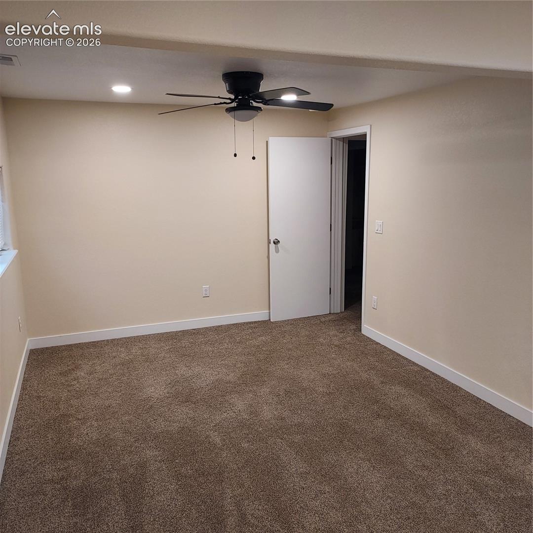 Neutral-toned carpeted flooring, recessed ceiling lighting, and a dark-finish ceiling fan with integrated lighting