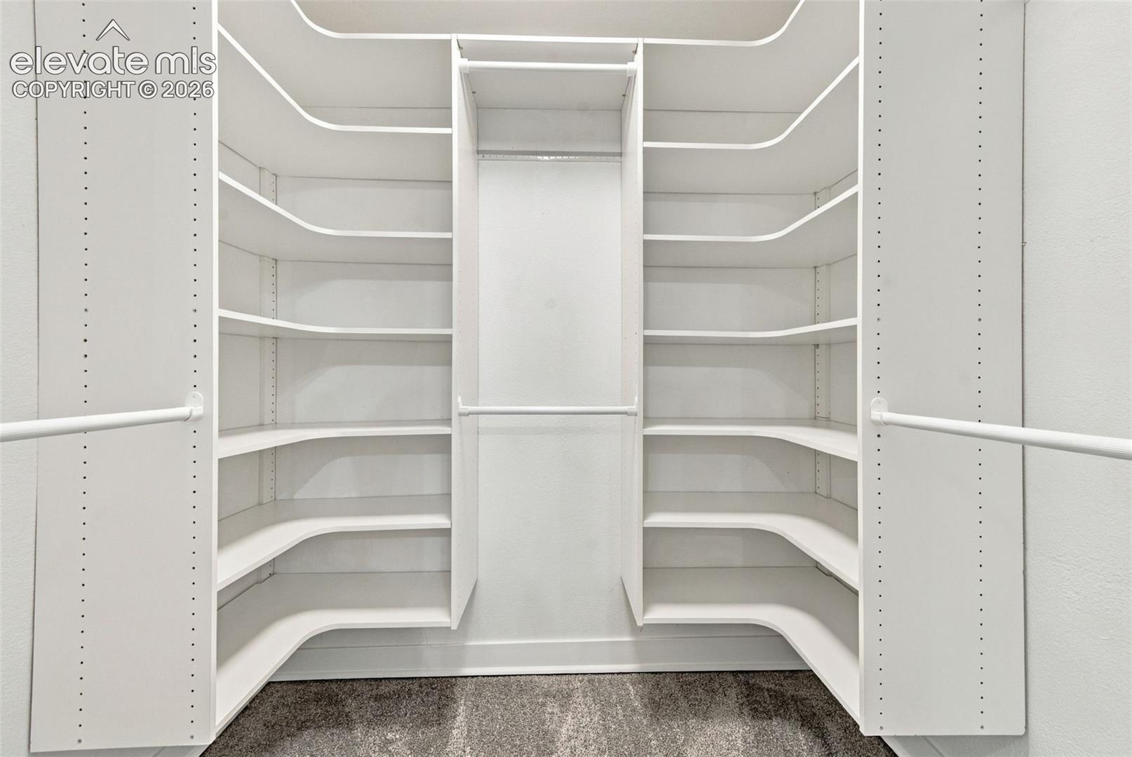 Custom walk-in closet featuring floor-to-ceiling white shelving, adjustable rack configurations, and carpeted flooring