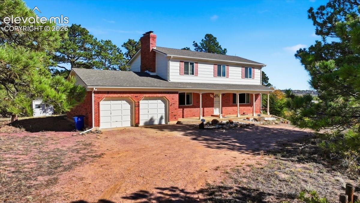 Two-story residence featuring a brick and horizontal siding exterior, a covered front porch, an attached two-car garage, and a brick chimney
