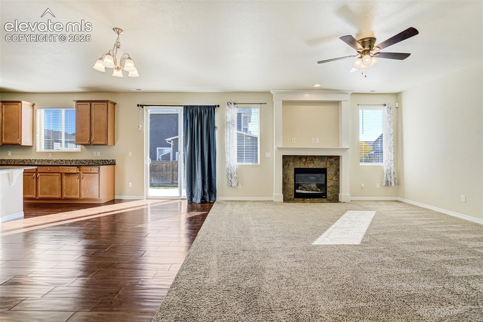 Open-concept living area with a stone-surround fireplace, built-in media niche, and ceiling fan