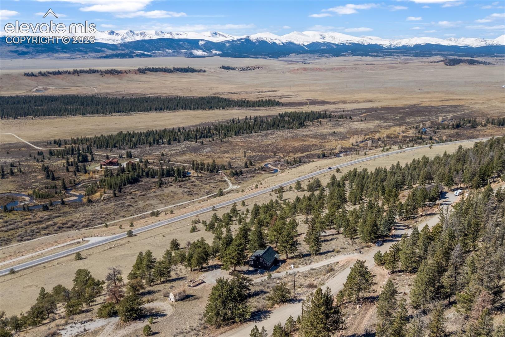Expansive lot featuring mature evergreen trees, open terrain, and a prominent mountain range backdrop