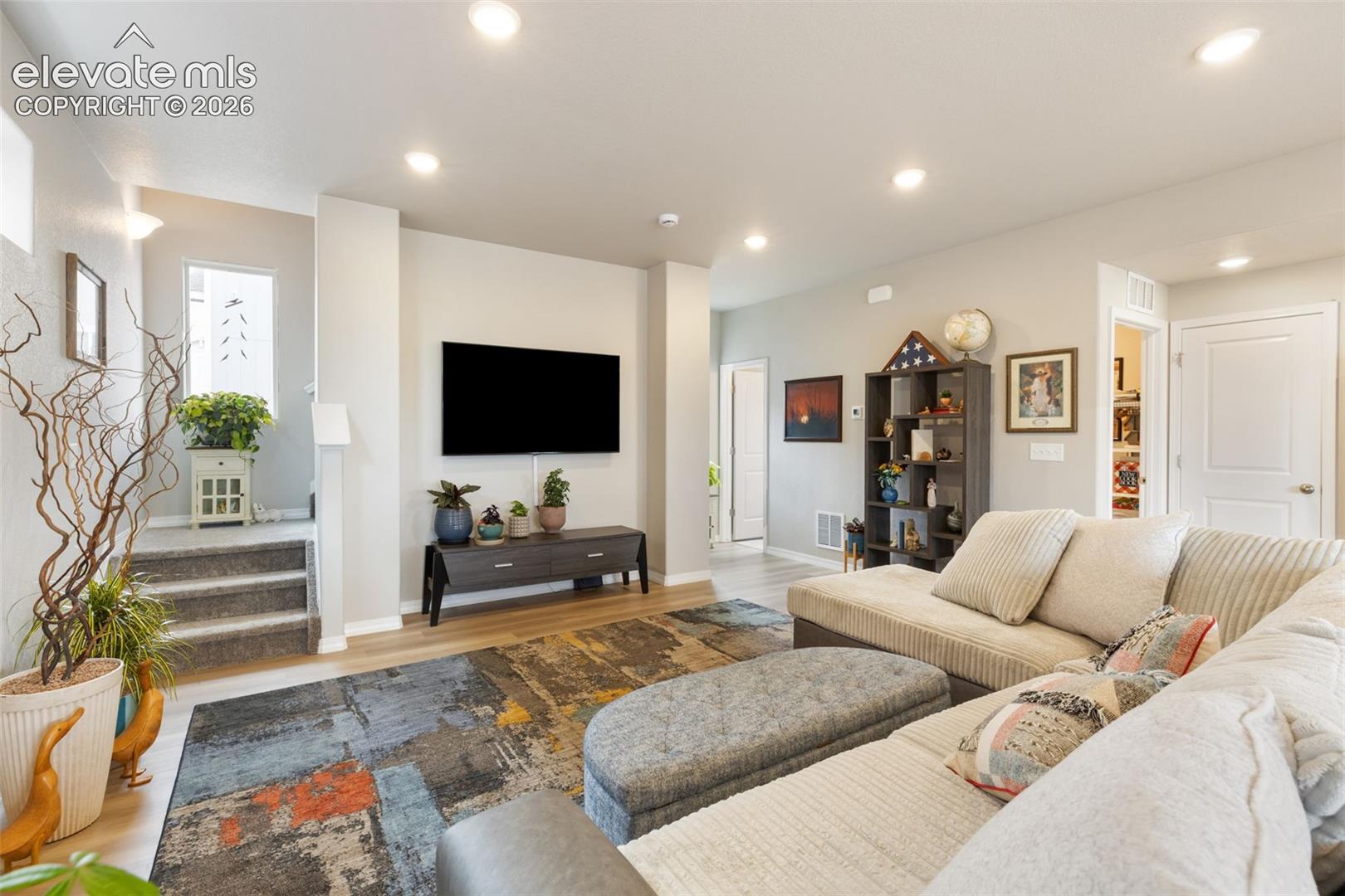 Open-concept living space featuring recessed lighting, wood-finish flooring, and light-toned wall finishes