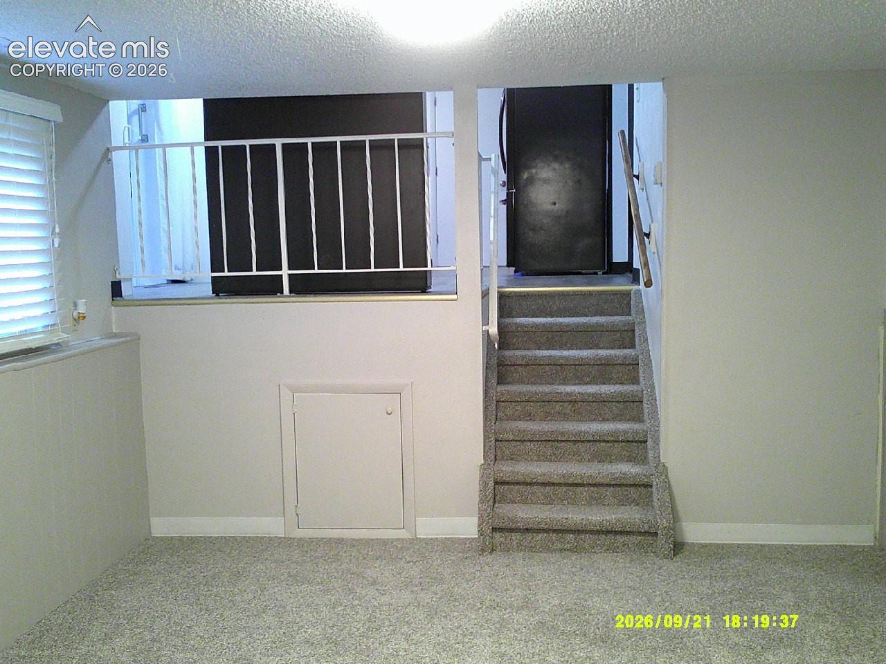 Carpeted flooring with a white railing and a window with blinds