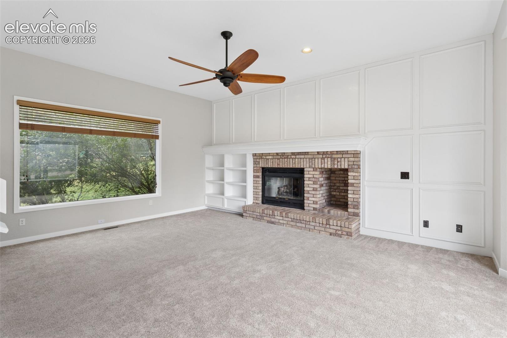 Brick fireplace with an integrated hearth, flanked by built-in shelving and paneled wall accents