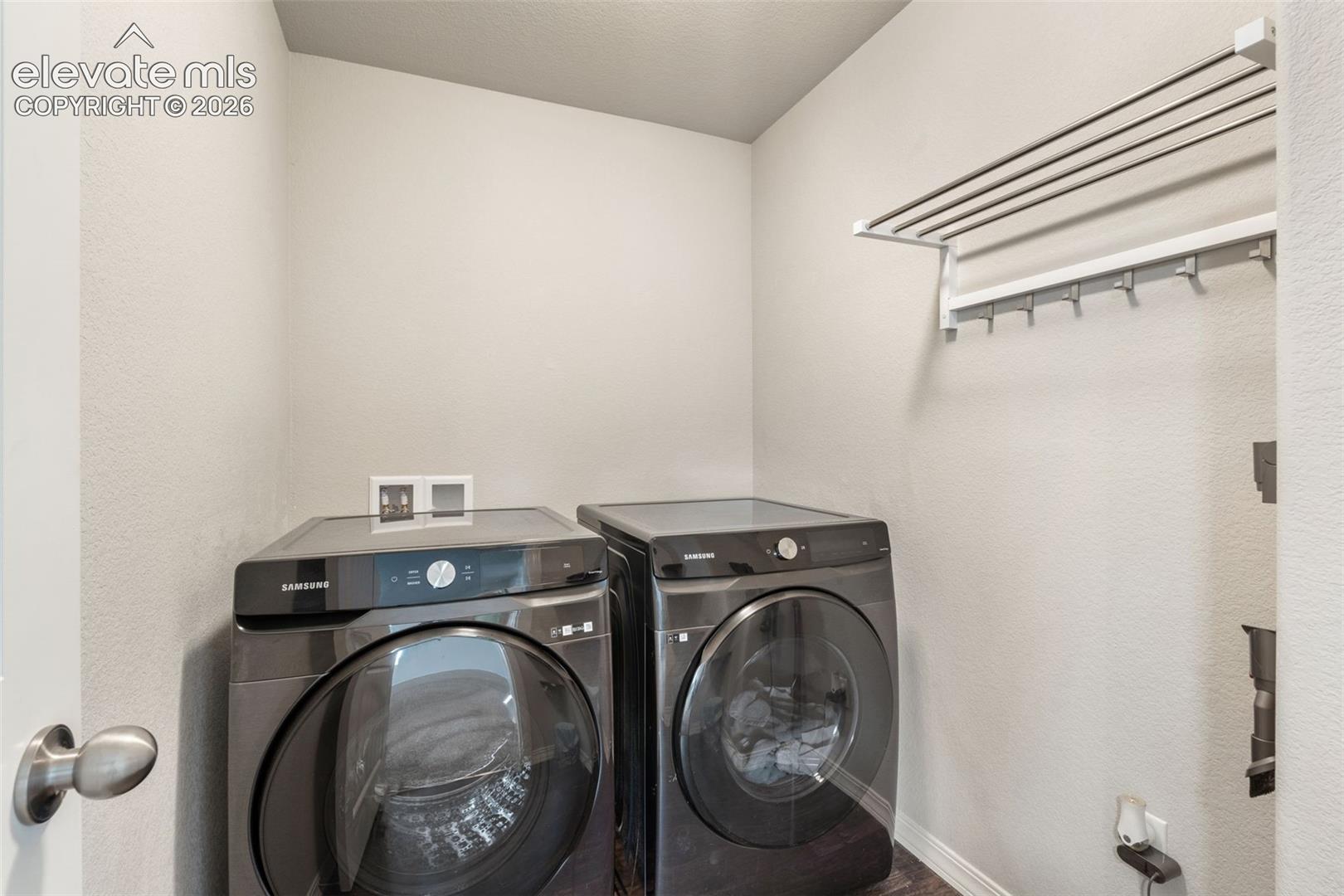 Compact utility space featuring a wall-mounted drying rack with hanging hooks