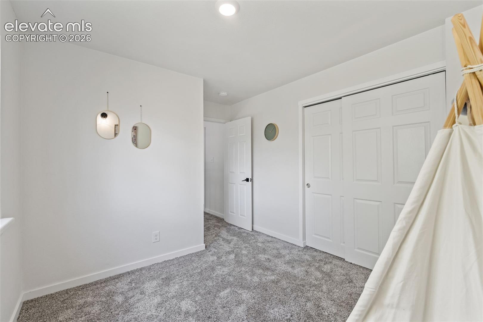 Neutral-toned wall-to-wall carpeting, recessed ceiling lighting, and a dual-panel closet with white swing-out doors
