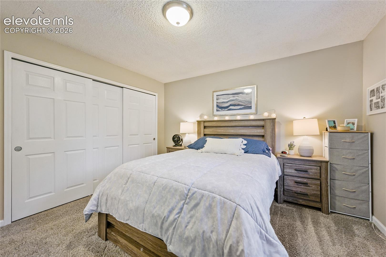 Neutral wall paint, plush carpeting, ceiling-mounted light fixture, and floor-to-ceiling closet with six-panel sliding doors