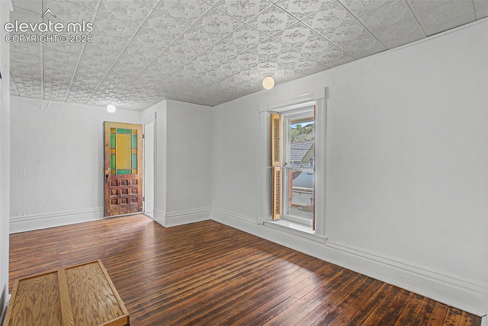 Secondary suite entrance featuring hardwood flooring and Victorian style ceiling tiles