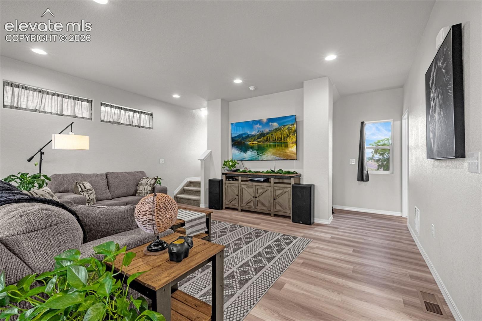 Open-concept living area featuring wood-finish flooring, recessed lighting, and a wall-mounted television