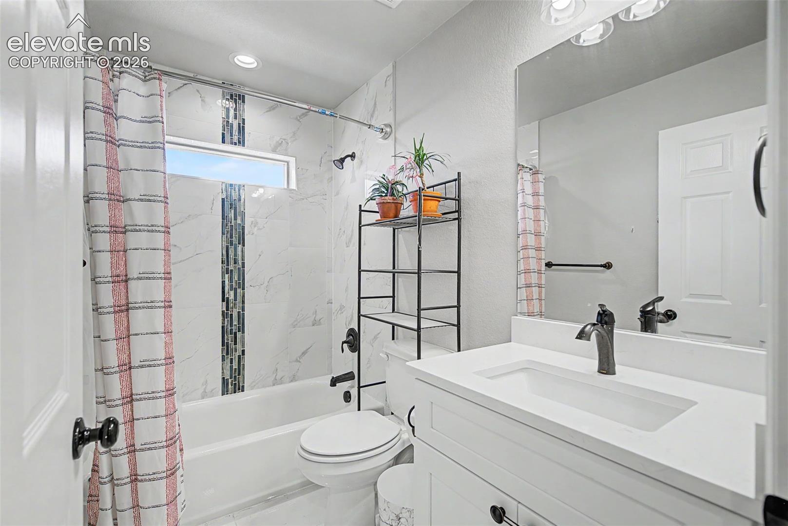 Bathroom featuring white vanity with integrated sink, rectangular mirror, and matte black fixtures