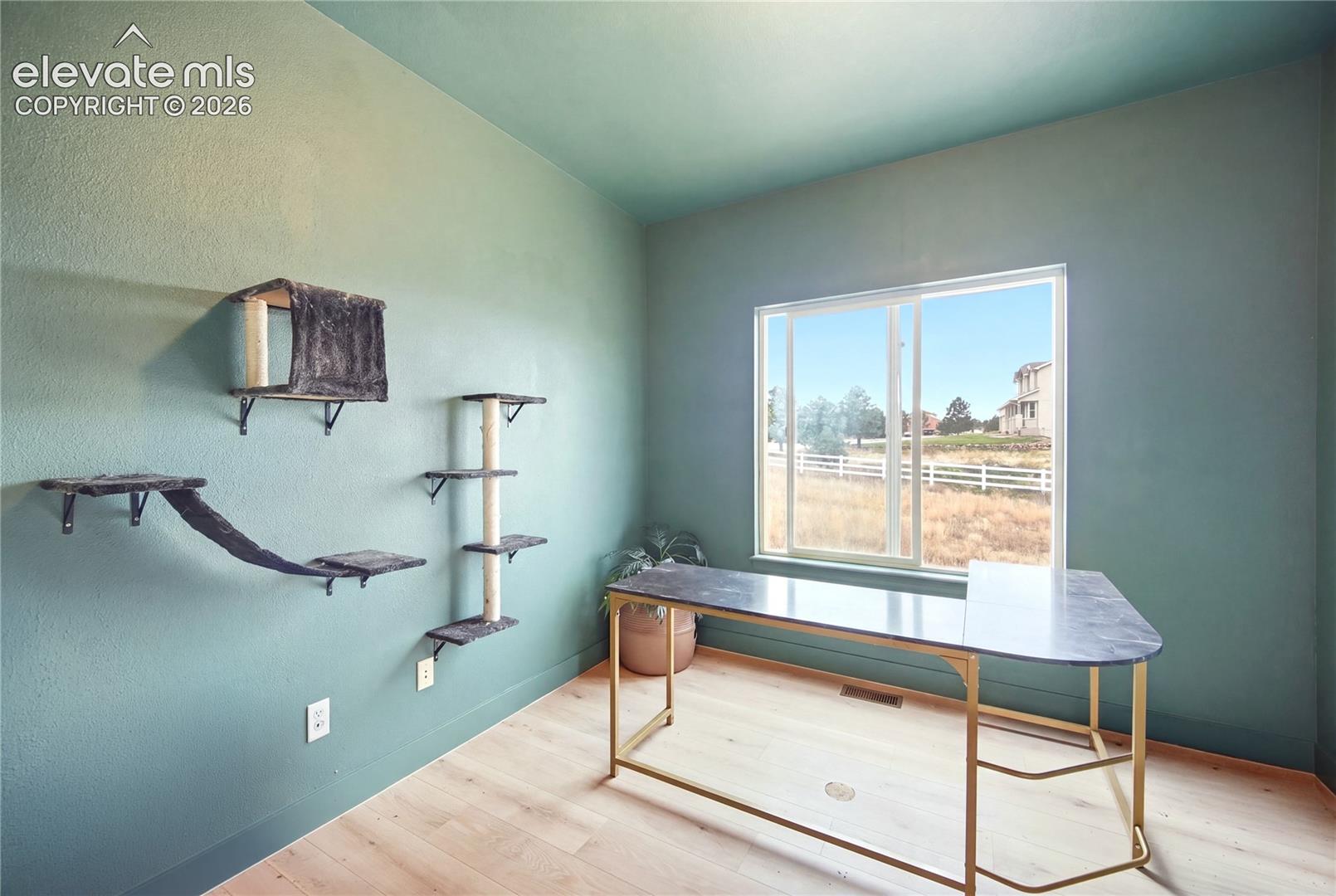 Room featuring wood-finish flooring, a dual-pane sliding window, and matte-finished wall surfaces