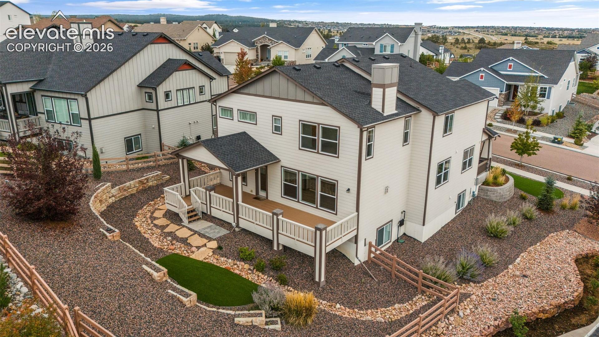 Rear exterior featuring a deck with partially covered patio, and stepped hardscaping with artificial turf
