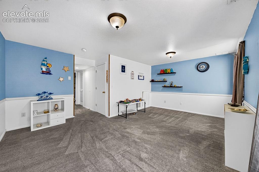 Recessed ceiling lighting, durable carpeting, wall shelving, and white wainscoting
