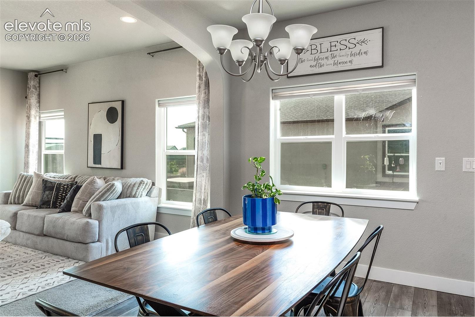 Dining area featuring a wood-finish table, a five-light chandelier, and multiple windows 