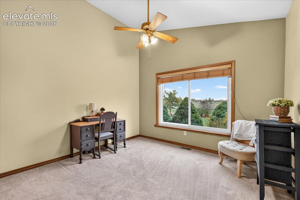 Vaulted ceilings, carpeted flooring, large picture window with natural scenery, and central ceiling fan with integrated lighting