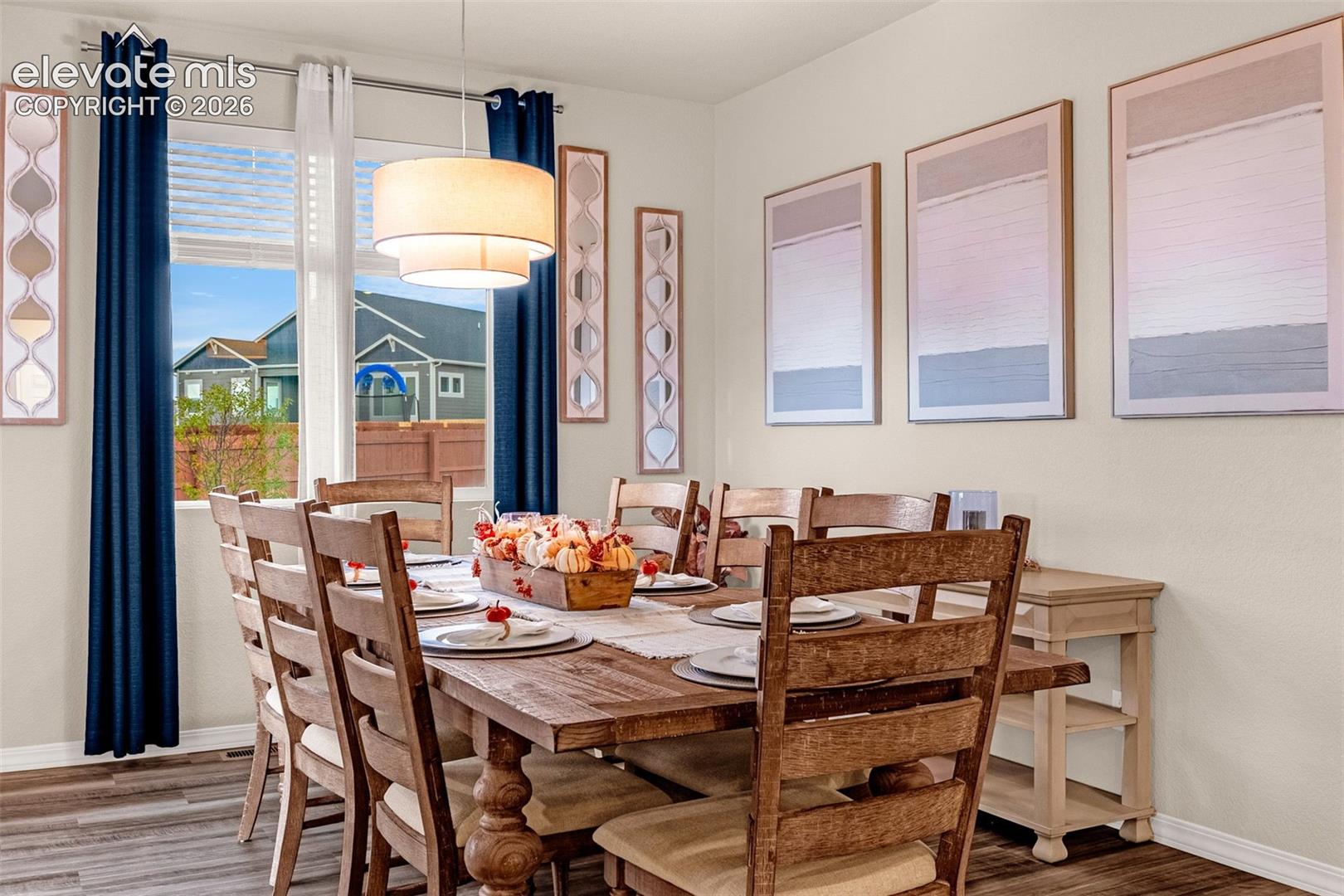 Hardwood-style flooring, a large window, a tiered drum pendant light, and neutral wall tones