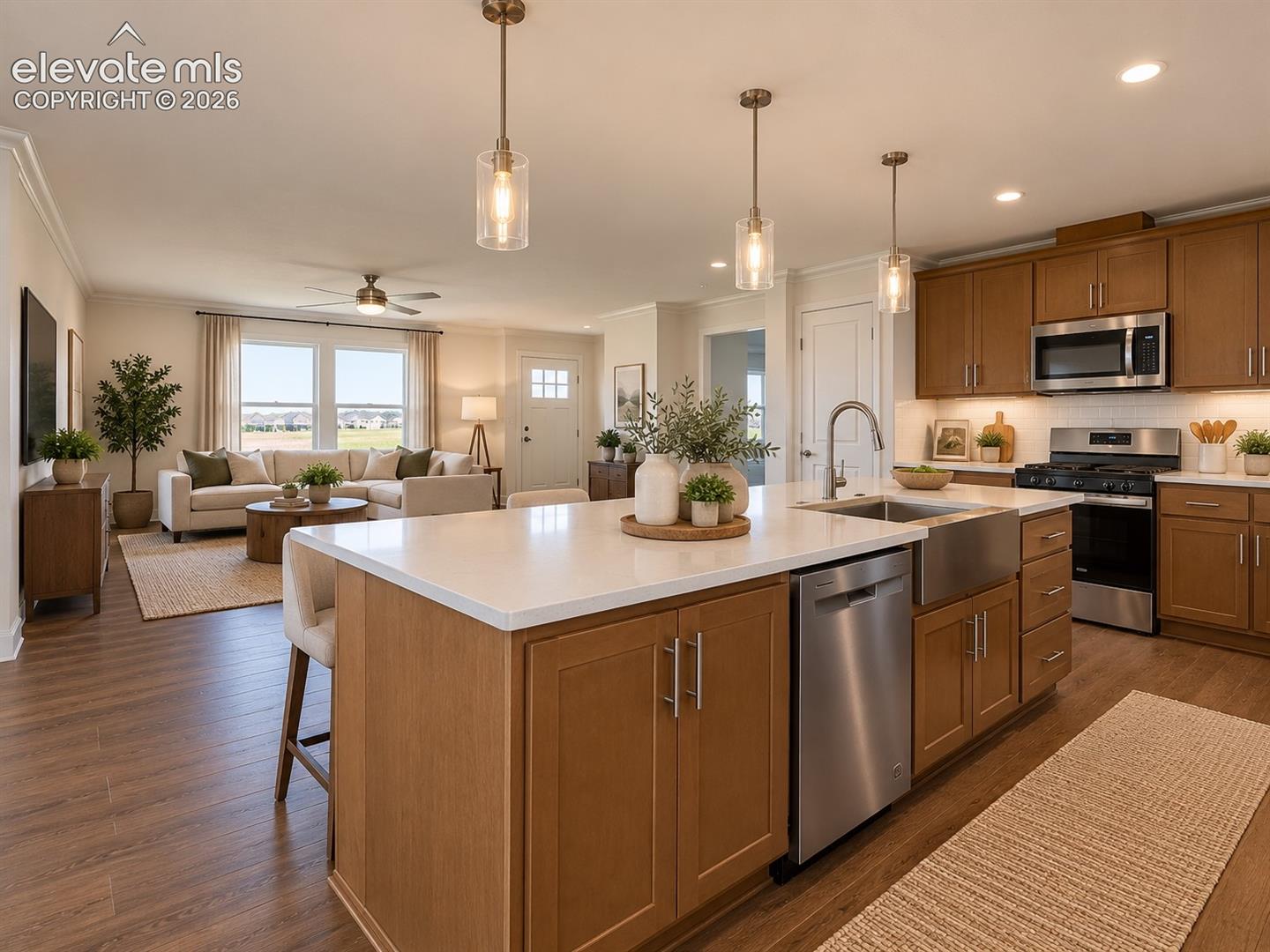 Kitchen & Great Room – The large center island anchors the open kitchen, with stainless steel appliances, abundant cabinetry, pendant lighting, and a direct sightline into the adjoining living area.