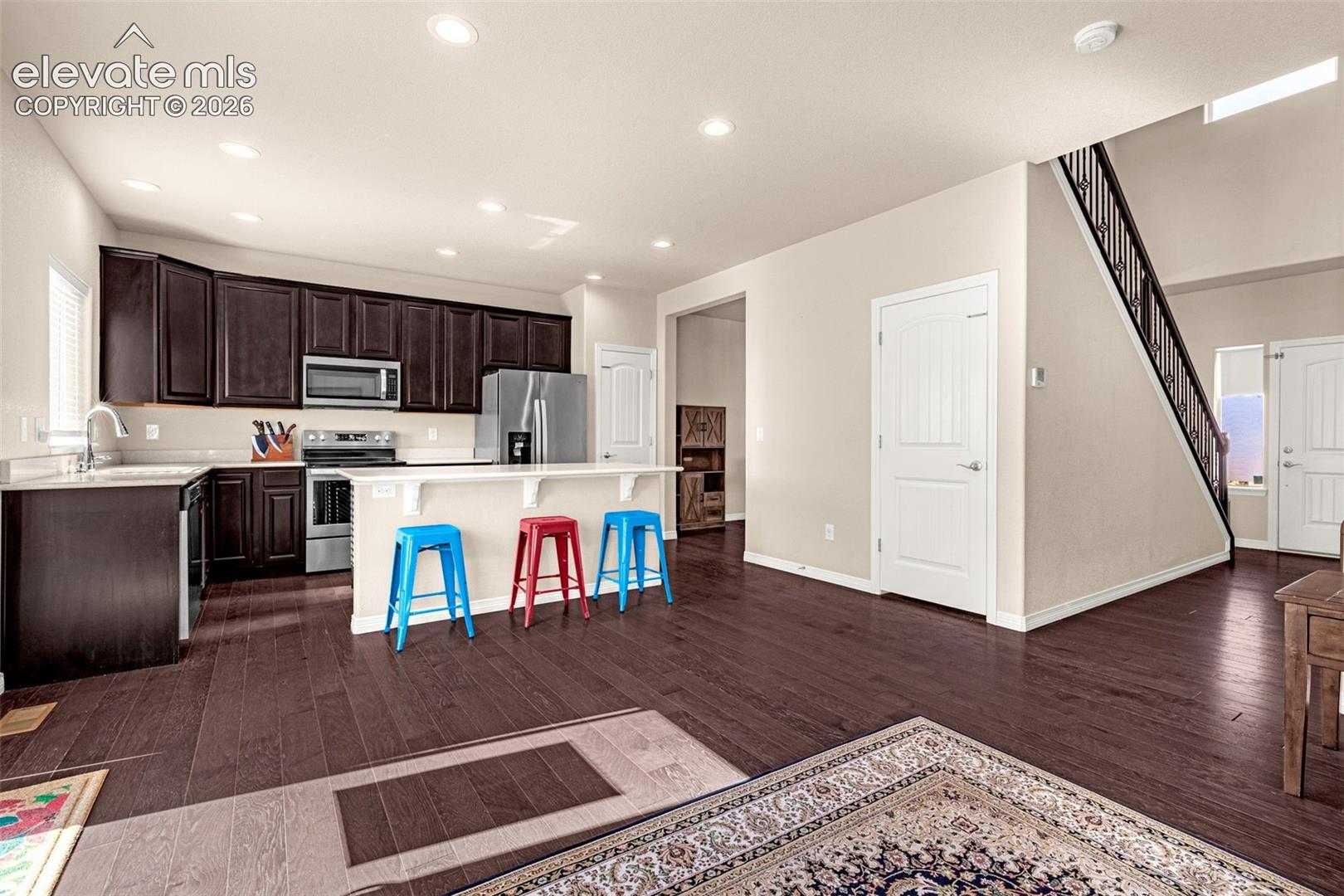 Kitchen featuring dark wood cabinetry, stainless steel appliances, and an island with counter seating