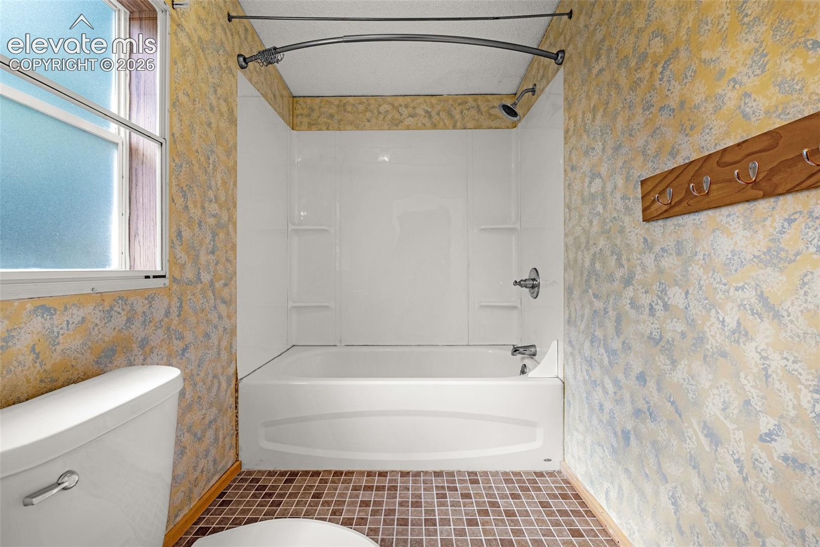 Bathtub and shower combination with white surround, chrome fixtures, and a curved shower rod