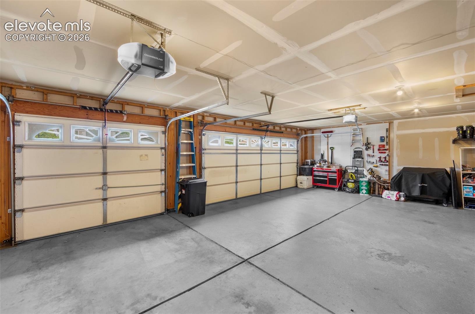 Spacious two-car garage featuring a concrete floor, two individual garage doors with upper window panels, and exposed ceiling joists