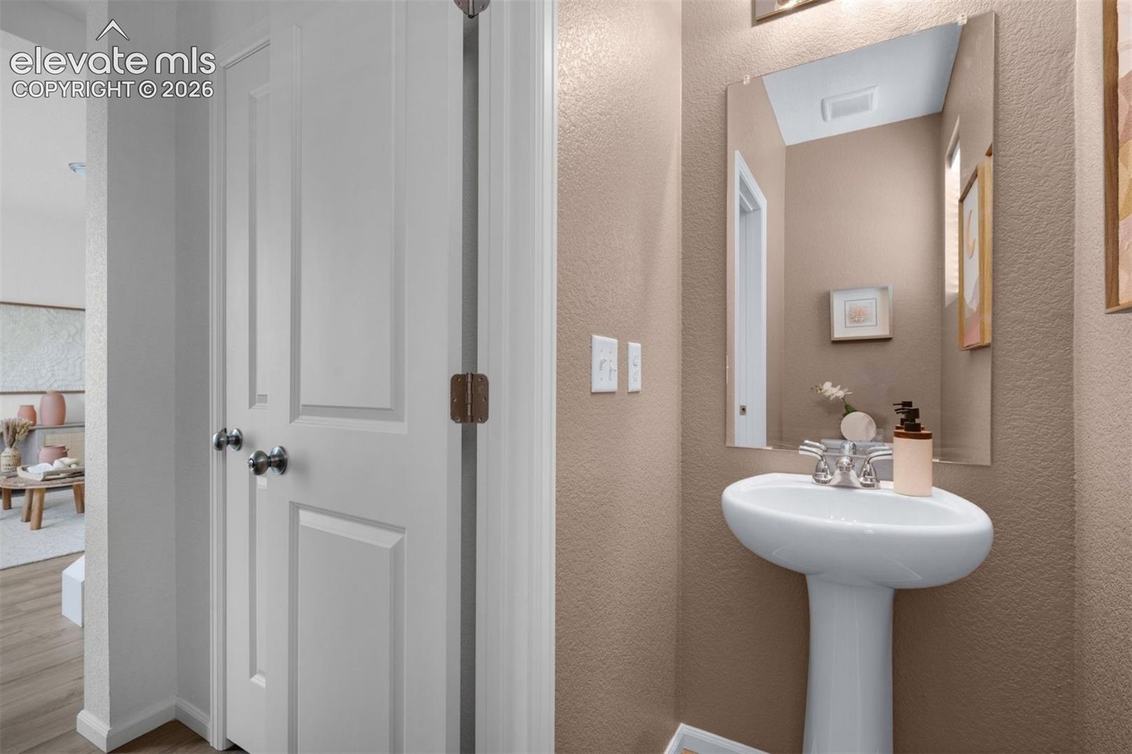 Pedestal sink with chrome faucet, wall-mounted mirror, and neutral wall finish
*photos of a model home*