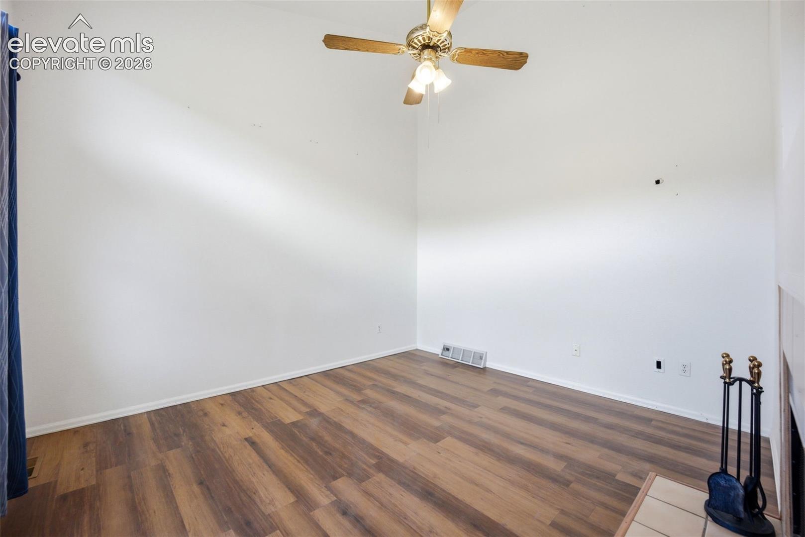 Interior space featuring wood-finish flooring, vaulted ceilings, and a central ceiling fan with integrated lighting