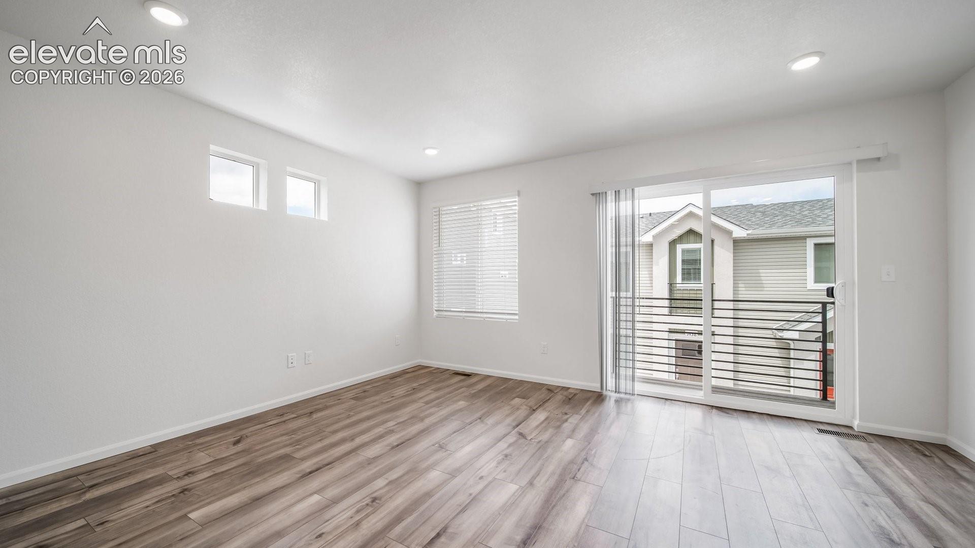 Recessed lighting, wood-finish flooring, sliding glass door, multiple windows, and a private balcony with horizontal railings
*photos of a model home*
