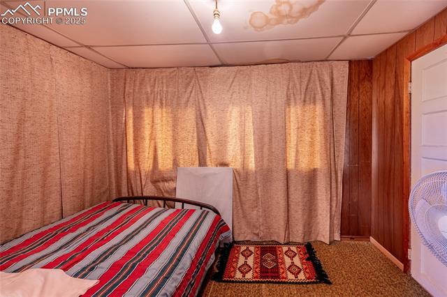 Bedroom featuring a paneled ceiling and wooden walls
