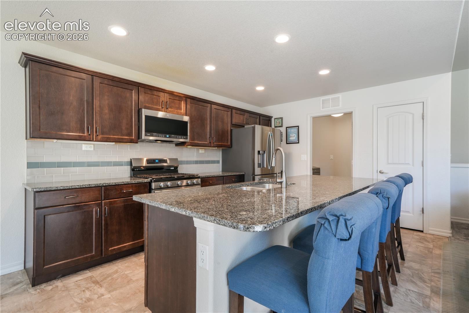 Kitchen with large island, granite countertops, gas range, abundant cabinets