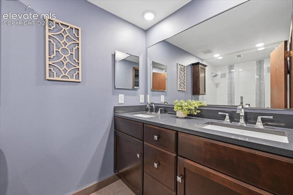 Dual vanity with dark wood-finish cabinetry, integrated sinks, and polished chrome fixtures