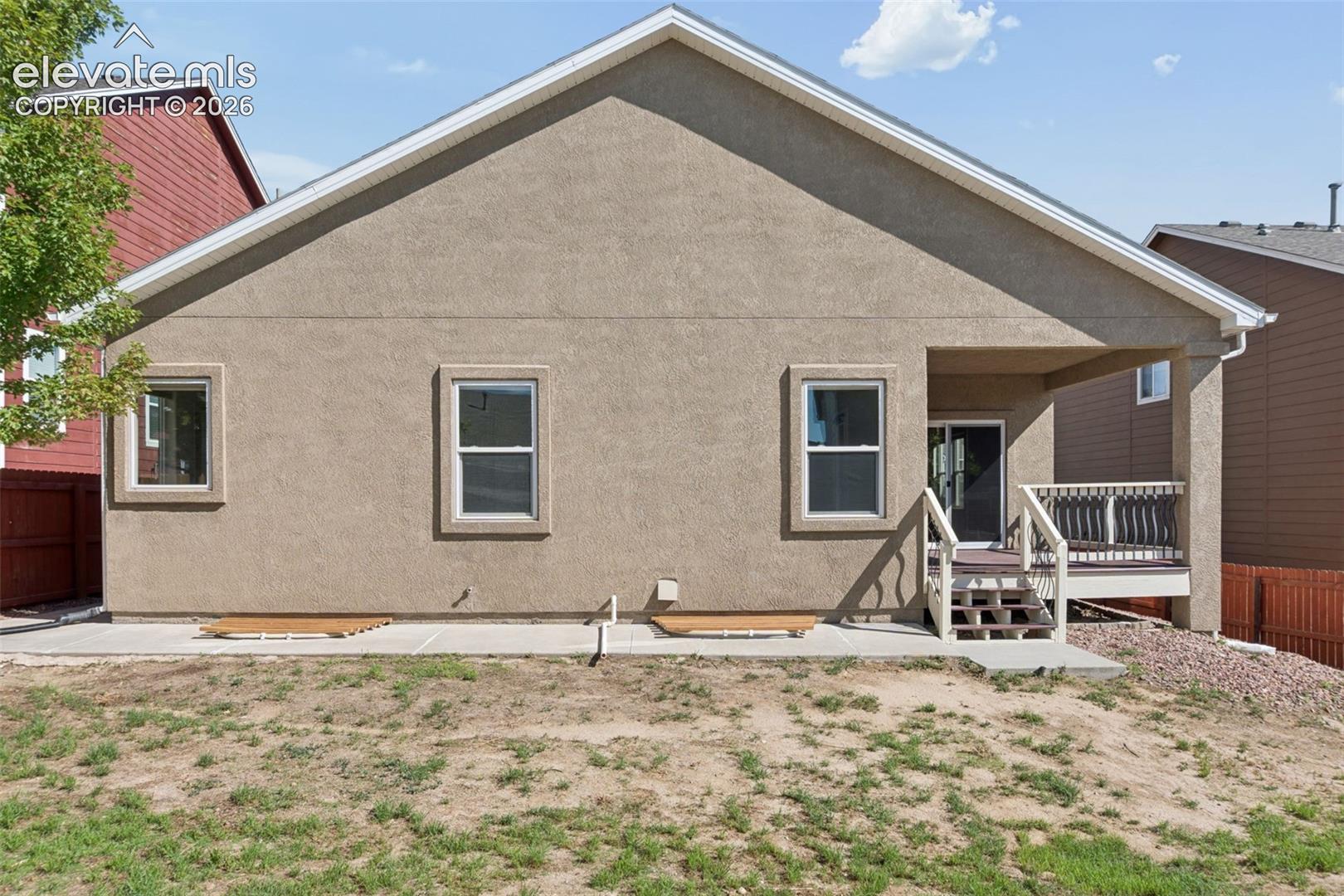 Rear exterior featuring a covered patio, wood-finish deck, and sliding glass door access