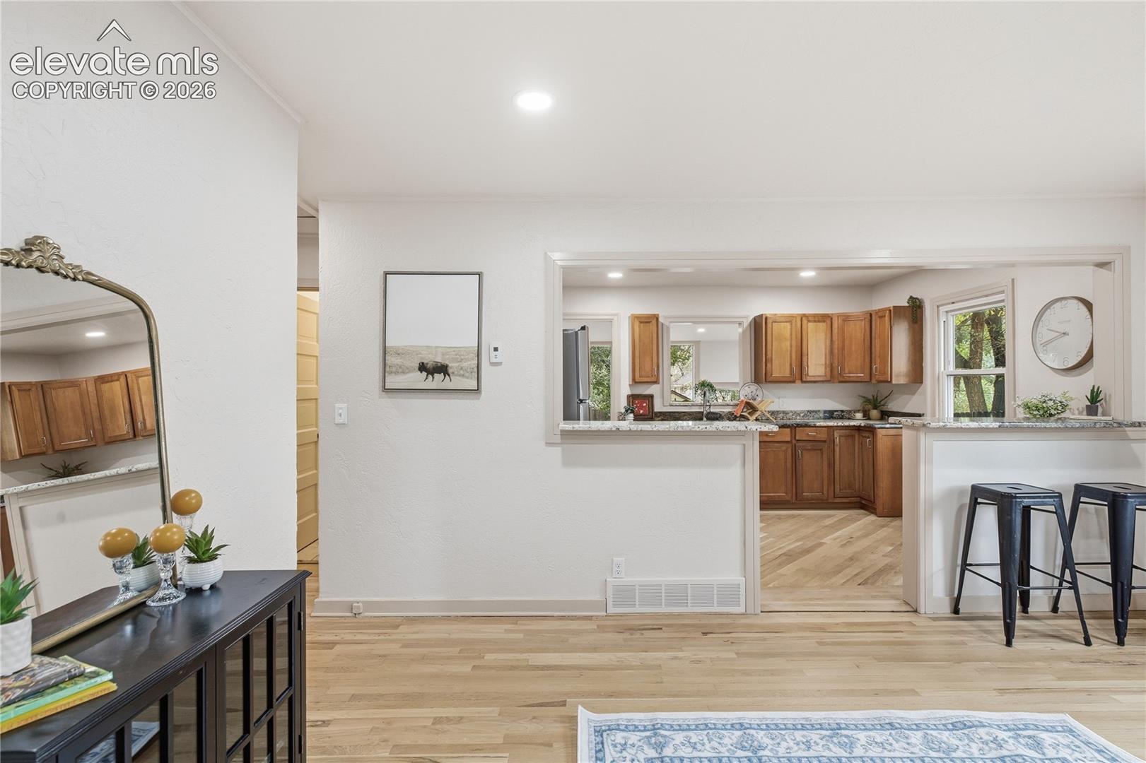 Interior featuring wood-finish flooring, recessed lighting, and a kitchen pass-through with a stone-surfaced breakfast bar