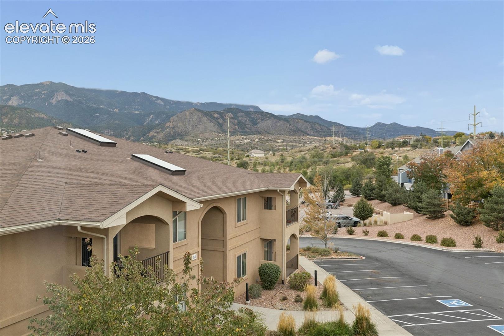 Exterior featuring stucco siding, roof-integrated skylights, arched entryway, and mountain backdrop