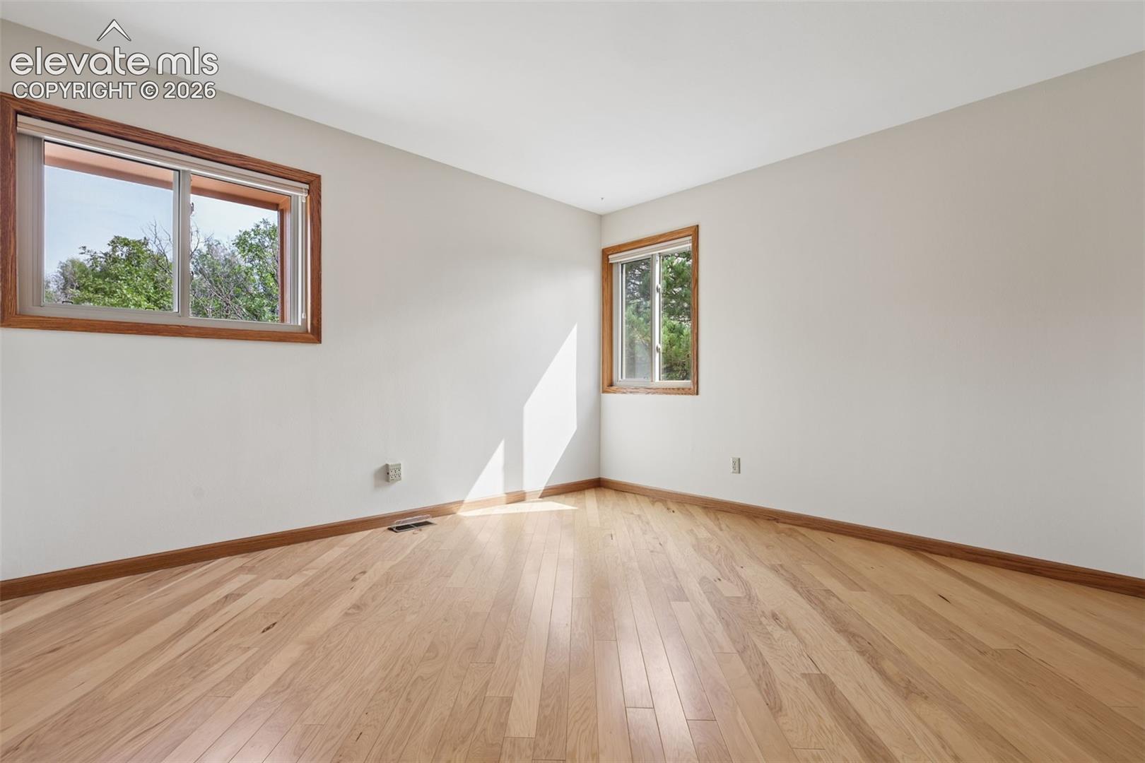 2nd bedroom with hardwood flooring and closet with built-in shelving.