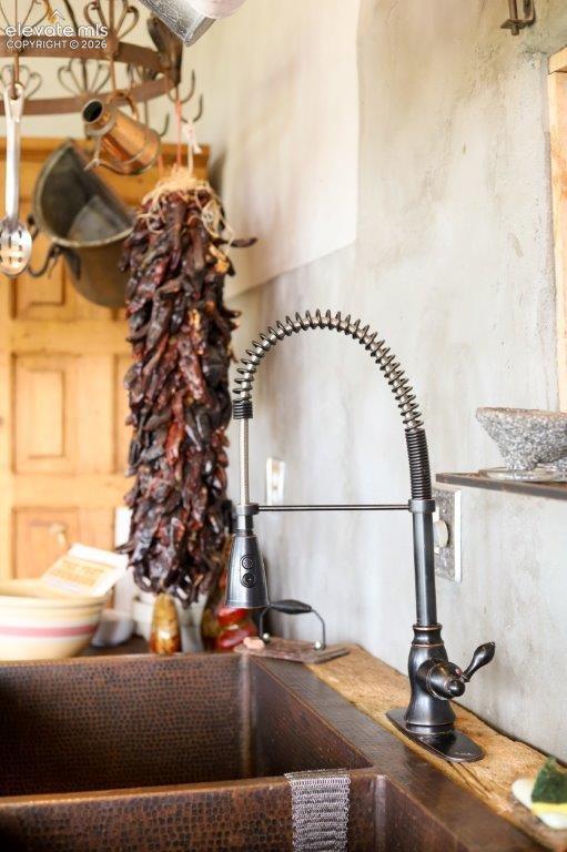 Hammered copper double-basin sink with an oil-rubbed bronze high-arc pull-down faucet, set into a distressed wood countertop