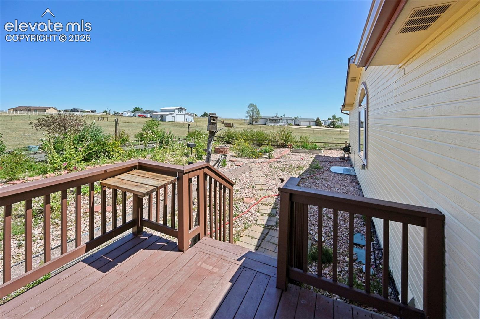 Wood-finish deck with integrated drop-leaf table, exterior siding, and a rounded arch window