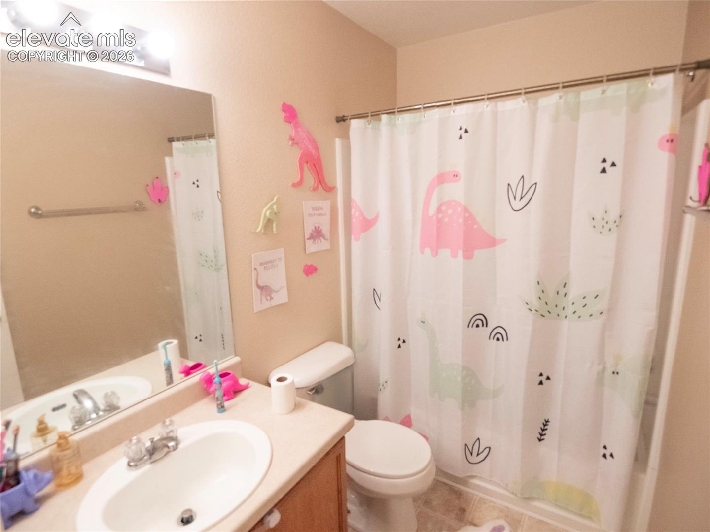 Bathroom featuring a single vanity with an integrated sink, a large wall mirror, and a shower-over-tub combination