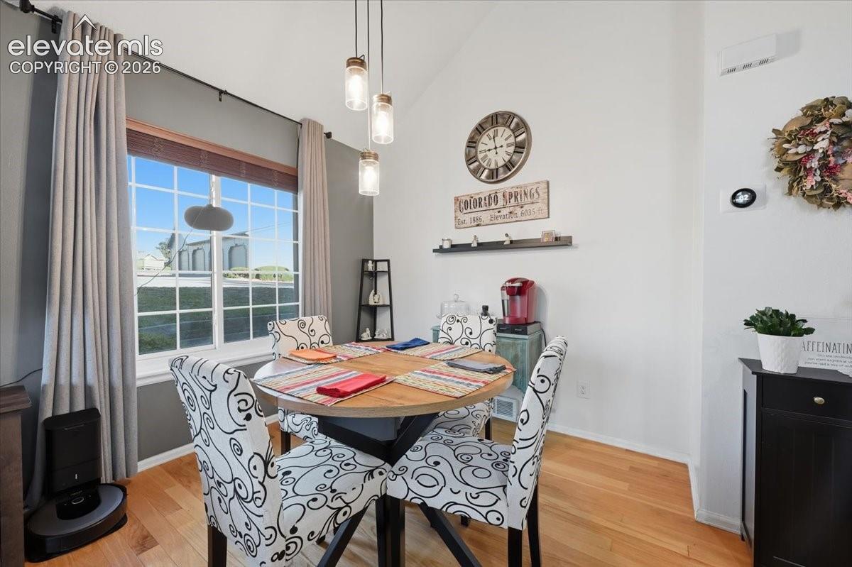 Vaulted ceilings, wood-finish flooring, and a multi-pendant glass light fixture